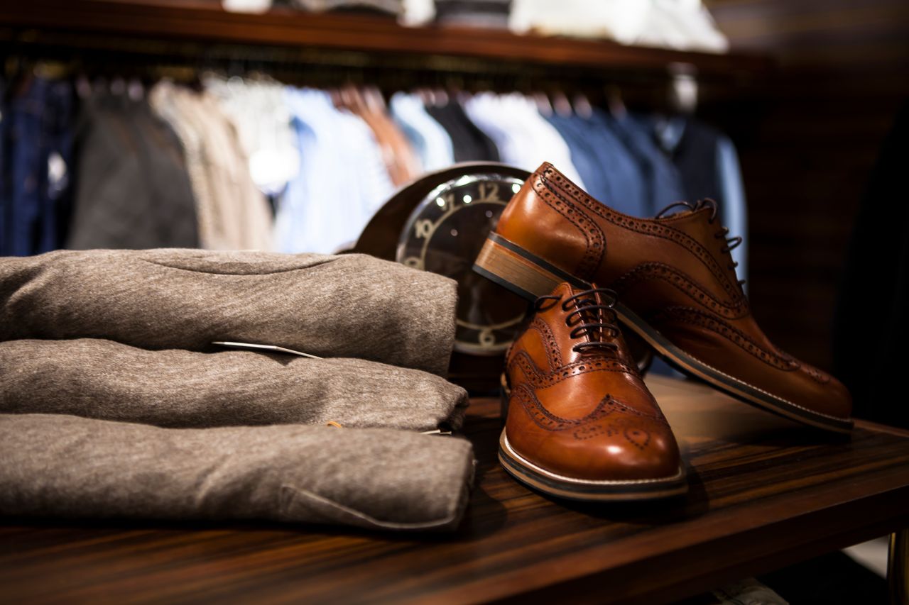 Services-01 Stylish leather shoes displayed with gray clothing in a chic boutique setting.