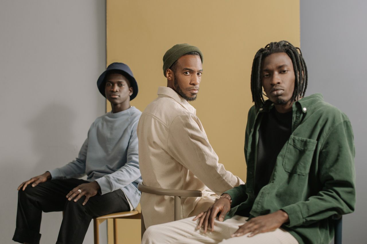 why-choose-us Three stylish men sitting in a minimalist studio with neutral tones and fashionable outfits.